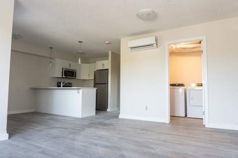 an empty kitchen and living room with a refrigerator and a sink
