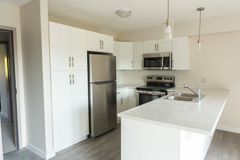 an empty kitchen with stainless steel appliances and white cabinets
