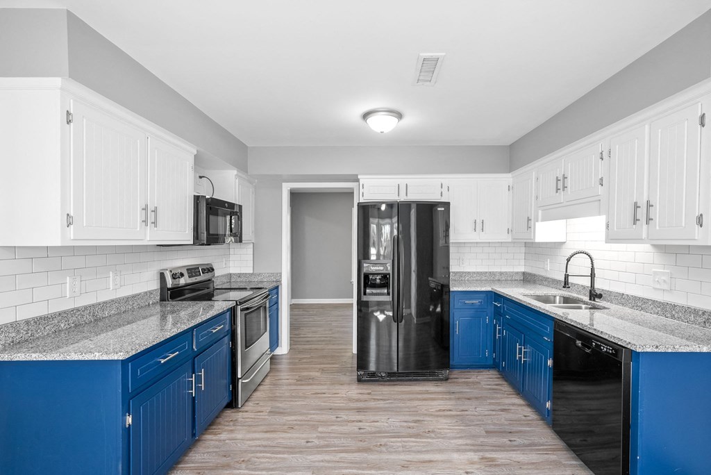 a kitchen with blue cabinets and a black refrigerator