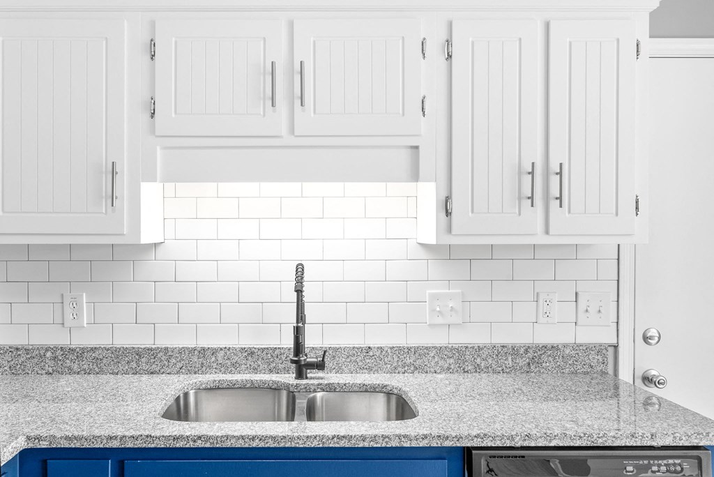 a white kitchen with white cabinets and a sink