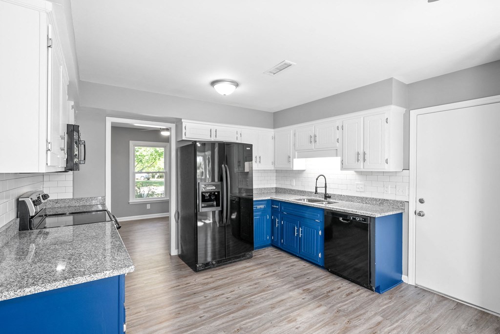 a kitchen with blue cabinets and a black refrigerator