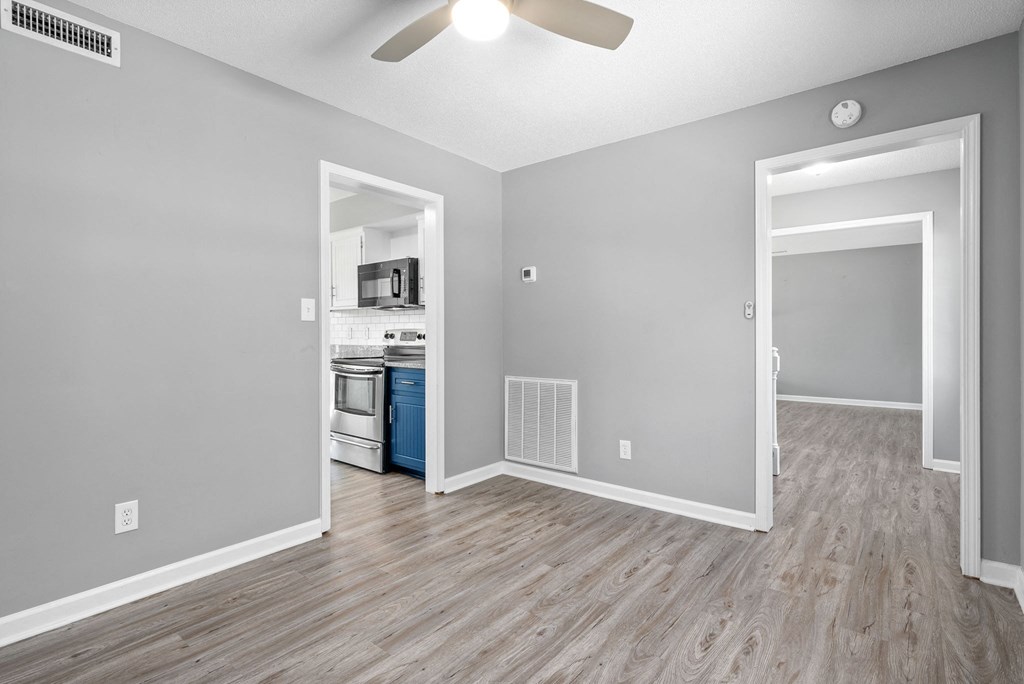 the living room and kitchen of a new home with wood floors and a ceiling fan