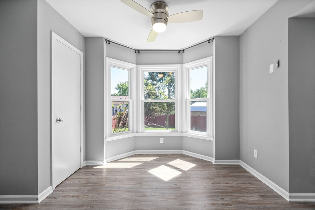 an empty room with three windows and a ceiling fan