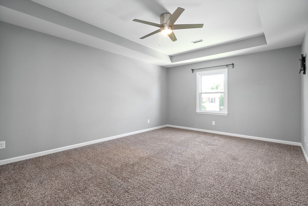 an empty room with carpet and a ceiling fan