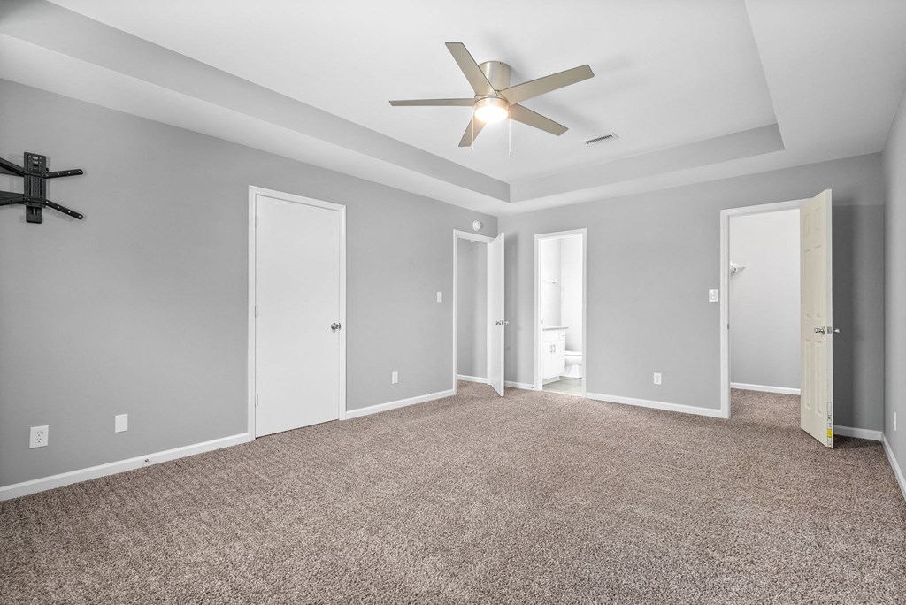an empty room with a ceiling fan and a door to a bathroom