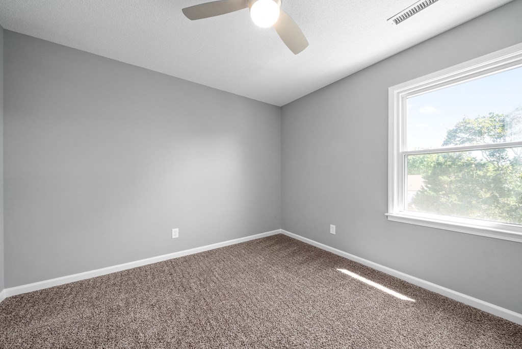 an empty room with gray walls and a window
