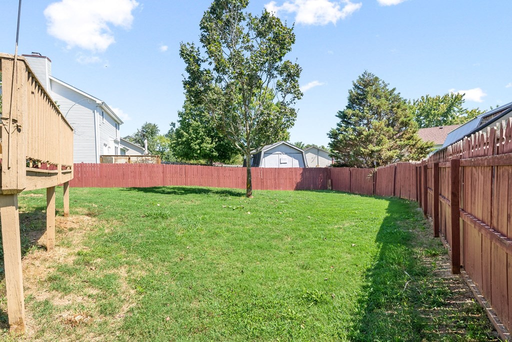 a backyard with a wooden fence and a yard with grass and trees