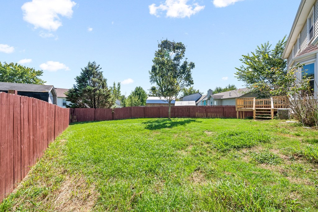 the backyard of a house with a fence and a green lawn