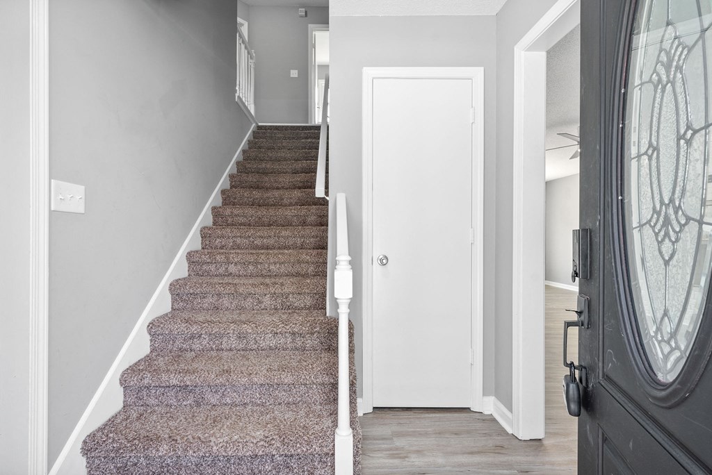 a view of the stairs from the entryway of a home with a black door