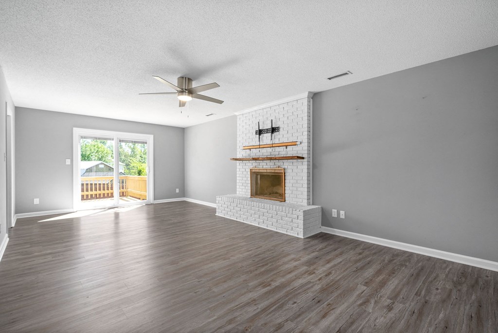 an empty living room with a fireplace and a ceiling fan