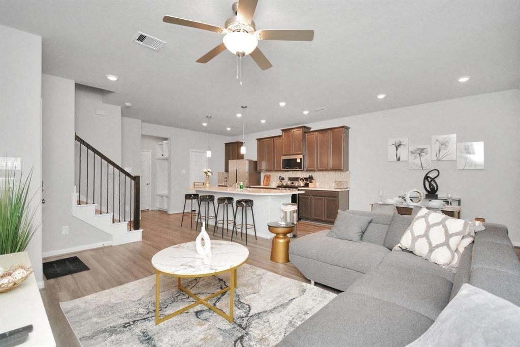 a living room and kitchen with a couch and a ceiling fan
