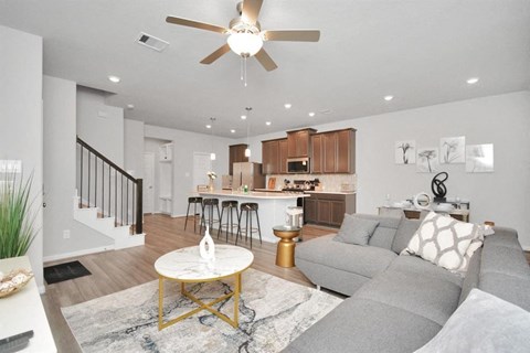 a living room and kitchen with a couch and a ceiling fan