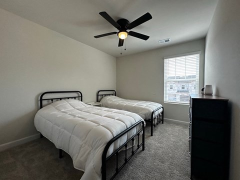 a bedroom with two beds and a ceiling fan