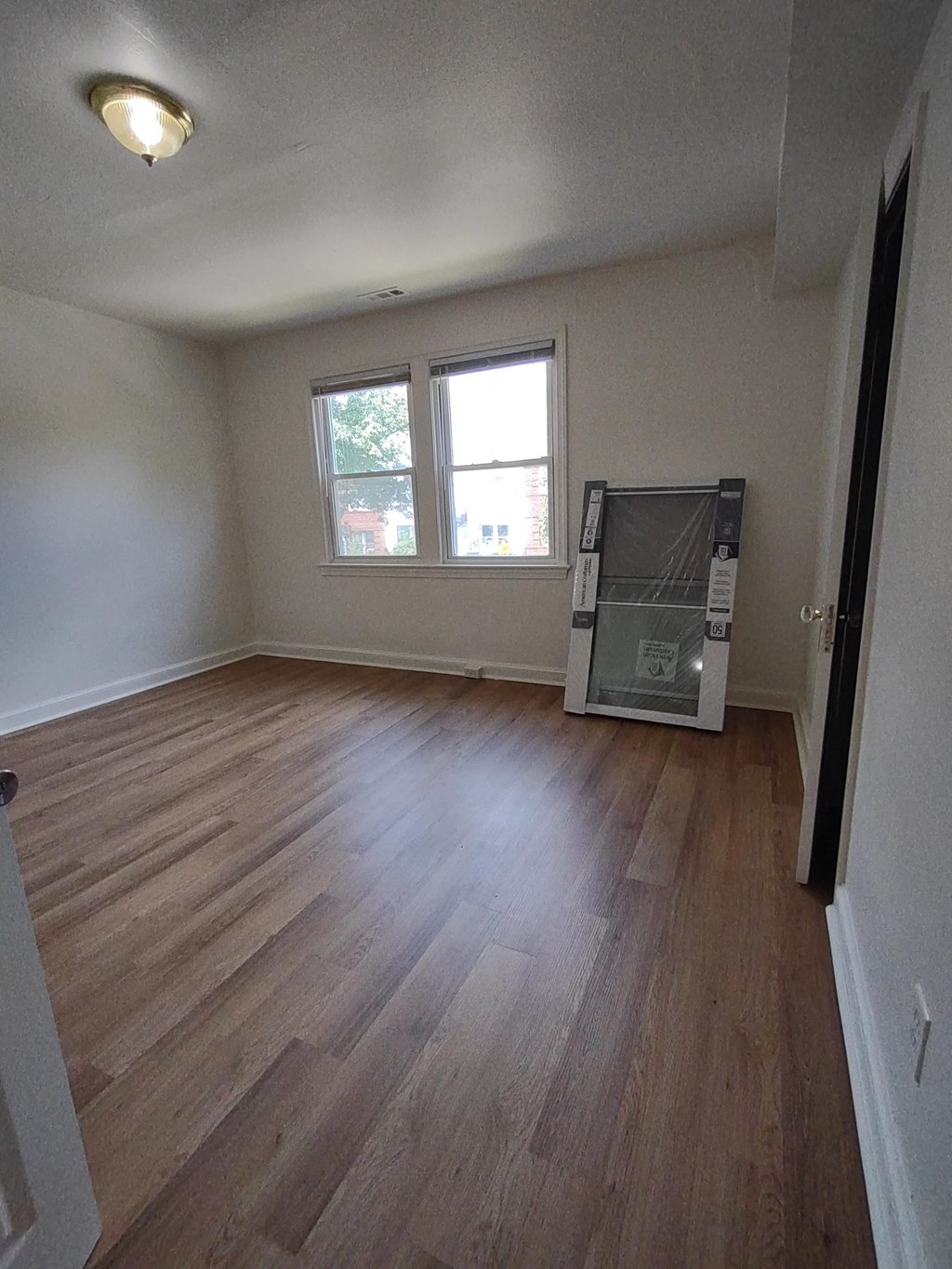 an empty living room with wooden floors and a window