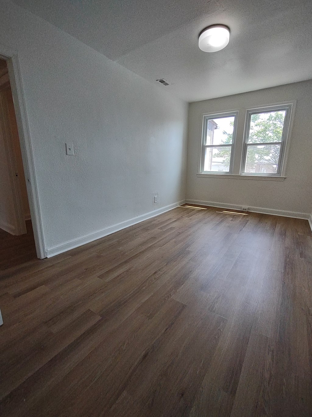 an empty living room with white walls and wooden floors