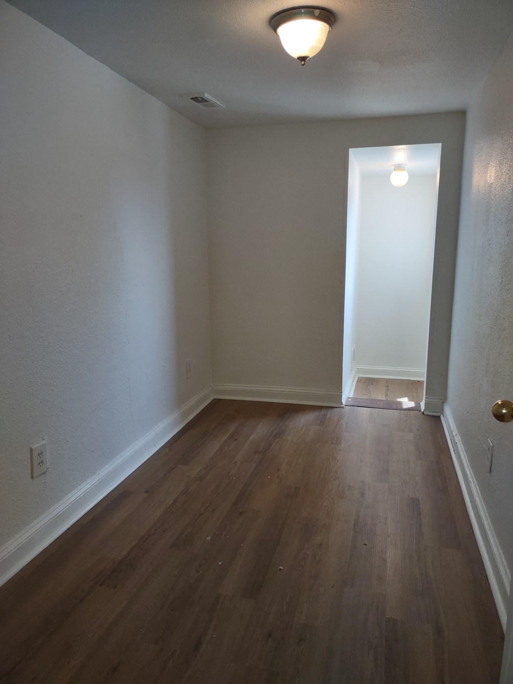 an empty living room with wood floors and white walls