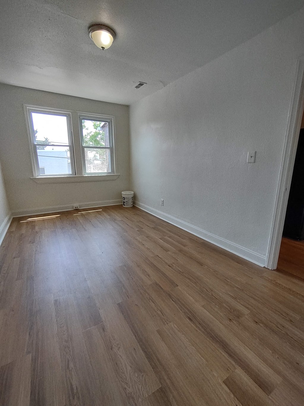 an empty living room with wooden floors and a window