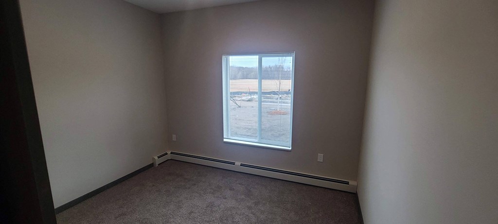 a bedroom with a large window and a carpet