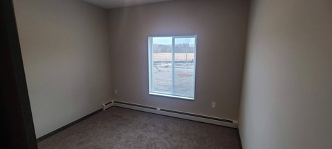 a bedroom with a large window and a carpet