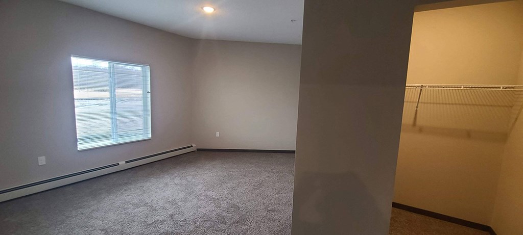 a bedroom with a large window and a carpeted floor