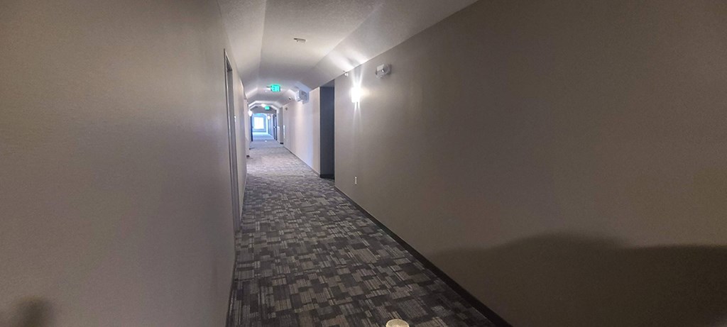a hallway with white walls and a tiled floor and a door