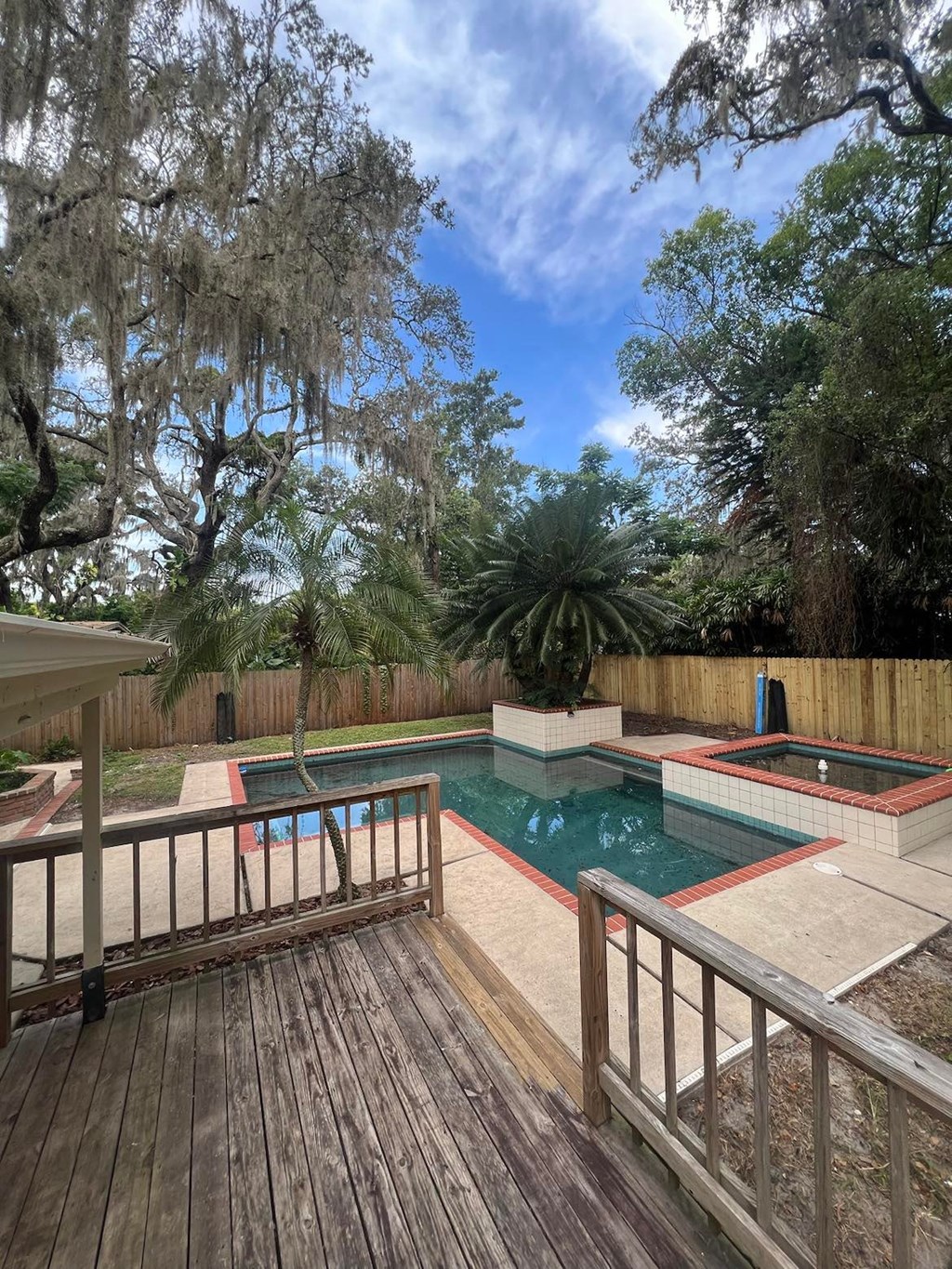 a pool and spa in a backyard with a wooden deck