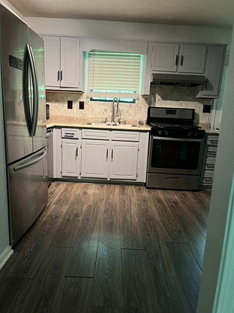 A kitchen with white cabinets and a stainless steel refrigerator.