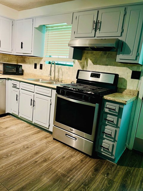 A kitchen with a black stove top oven and white cabinets.