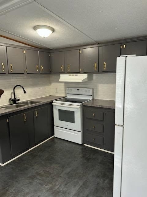 A kitchen with a white refrigerator, black cabinets, and a white stove top oven.