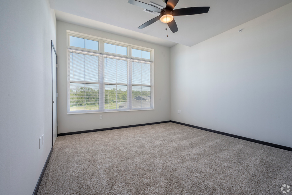 an empty living room with a ceiling fan and a window