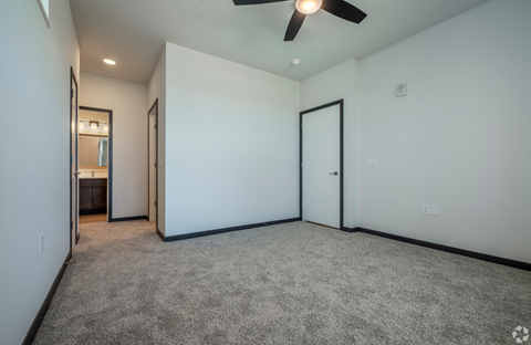 an empty living room with white walls and a ceiling fan