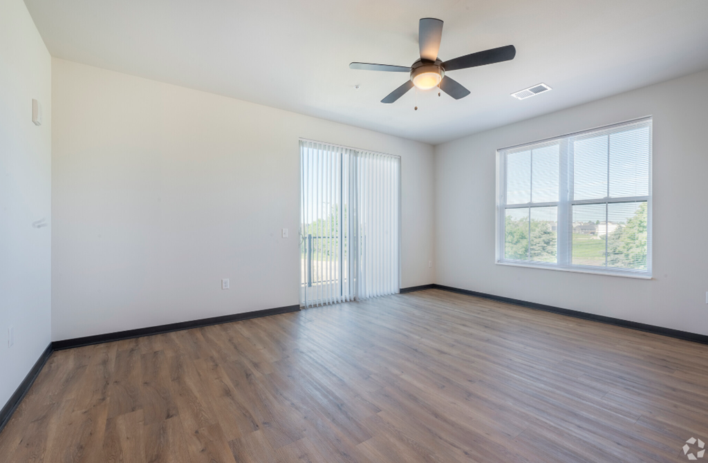 an empty living room with wood floors and a ceiling fan