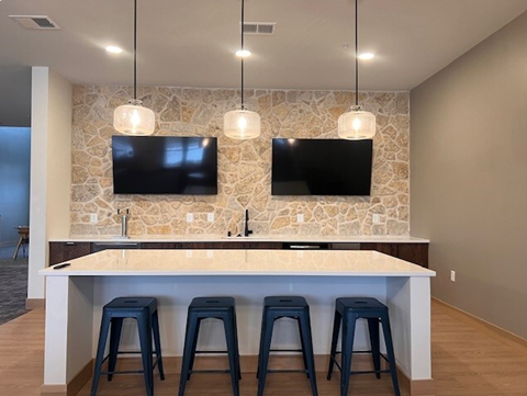 a bar with three stools and two televisions on the wall