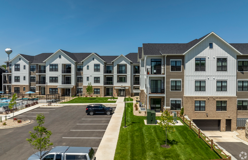an exterior view of an apartment complex with a car parked in a parking lot