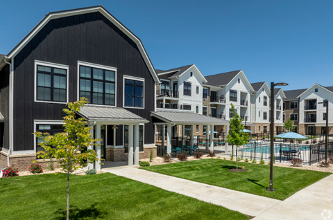 an exterior view of an apartment complex with a pool and lawn