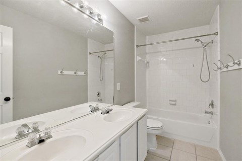 A white bathroom with a double sink vanity and a walk-in shower.