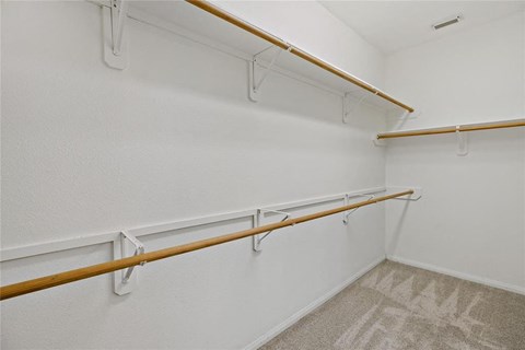 A white wall with a row of shelves and a carpet on the floor.