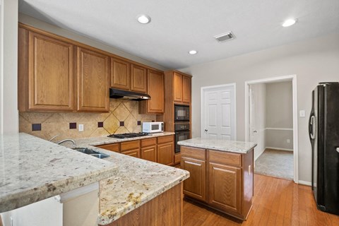 A kitchen with wooden cabinets and granite countertops.