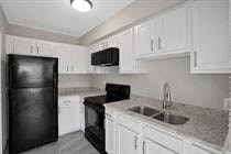 a white kitchen with a black refrigerator and a sink