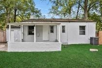 a small white house with a porch in the grass