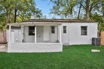 a small white house with a porch in the grass