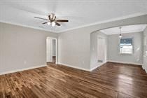an empty living room with white walls and a ceiling fan