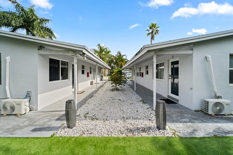 A row of white houses with air conditioning units on the ground.