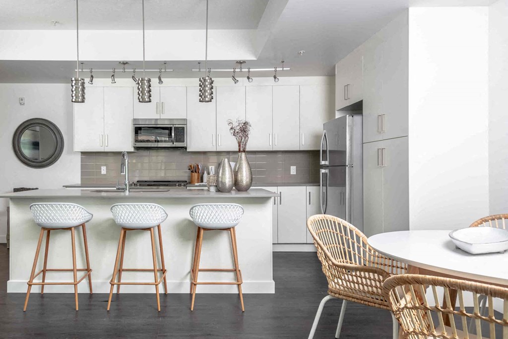 a kitchen with white cabinets and a white table and chairs