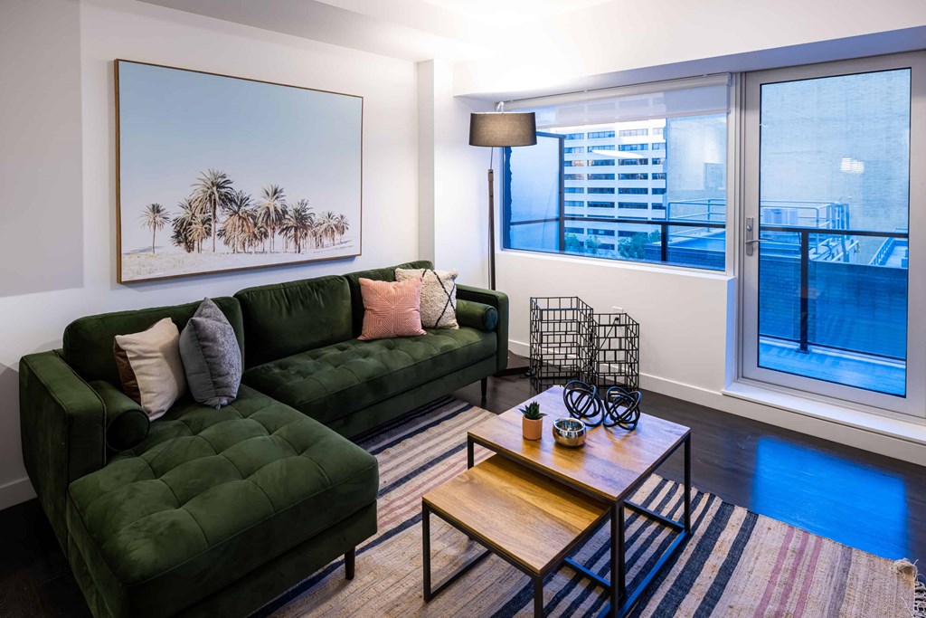 a living room with a green couch and a large window