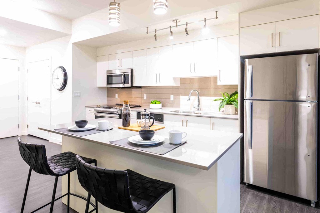 a modern kitchen with stainless steel appliances and white counter tops