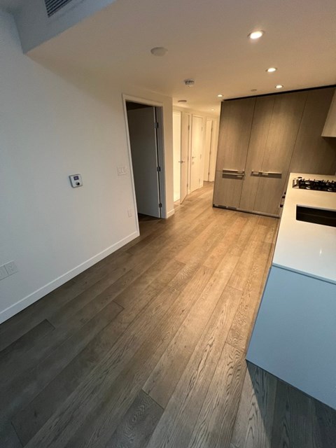 A kitchen with a white counter top and wooden floors.