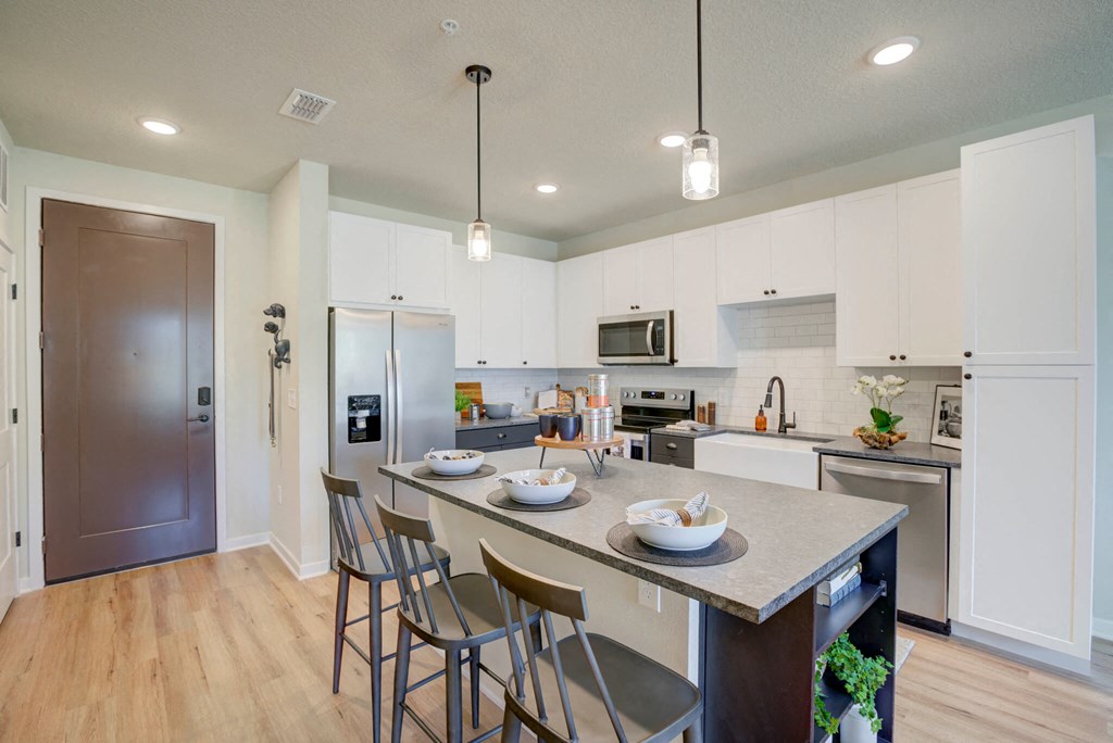 an open kitchen with a large island with three chairs