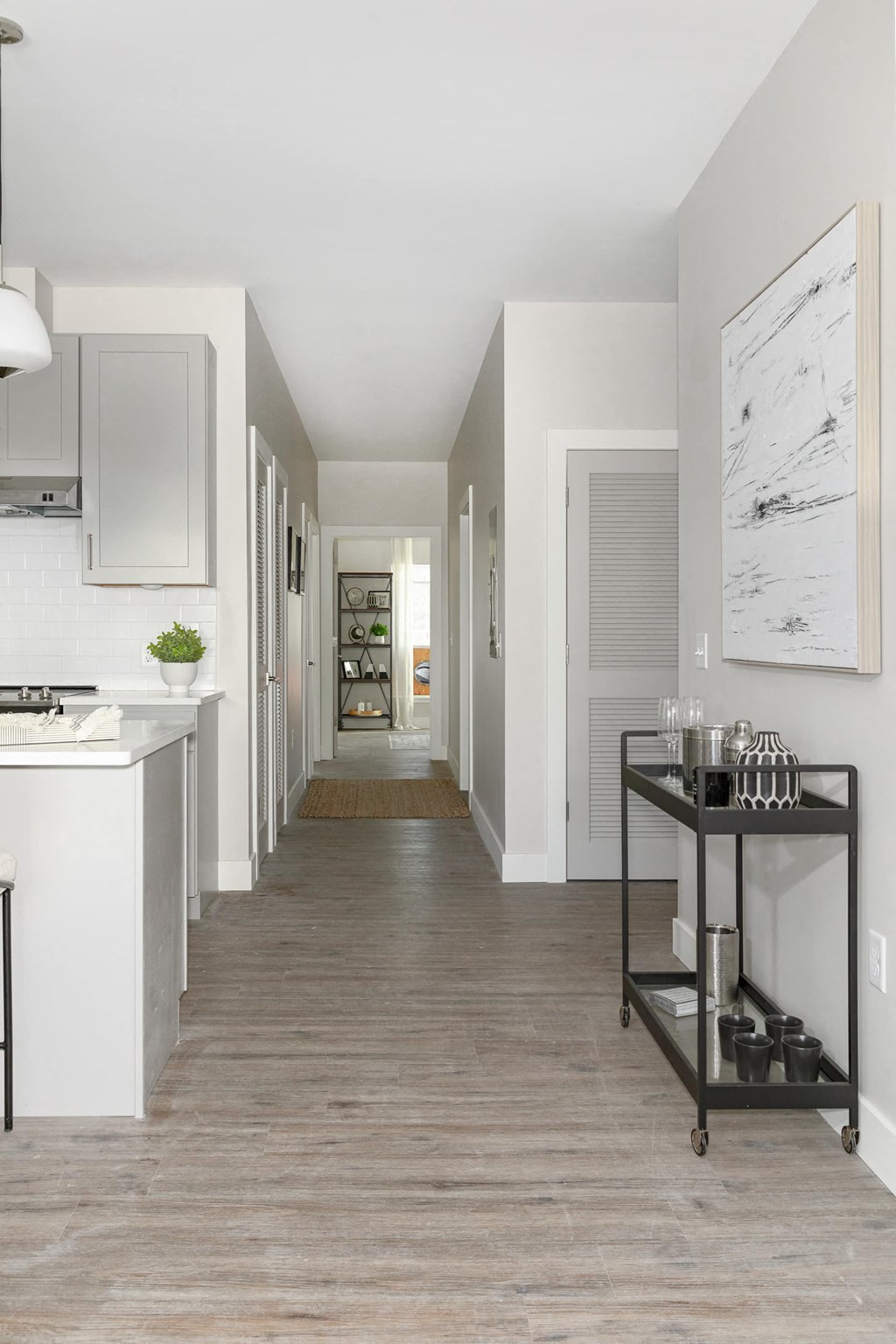 a long hallway with a kitchen and a pass through to a living room