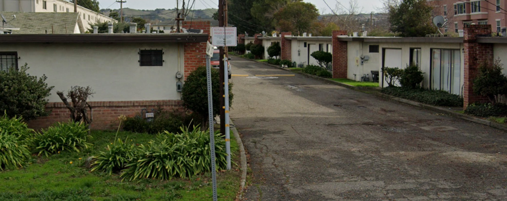 an empty street in a neighbourhood with buildings and a street sign